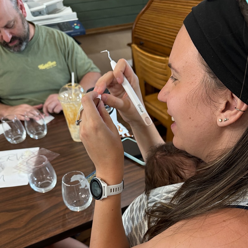 A man and woman working on wine glass etching at the Glenn A Jones MD Memorial Library adult programs