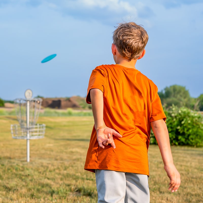 A boy plays disc golf with the disc golf game checked out from the Glenn A Jones MD Memorial Library