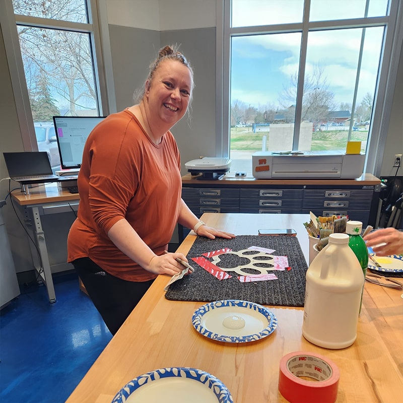 A woman works on a painting project at the Glenn A Jones MD Memorial Library Makerspace